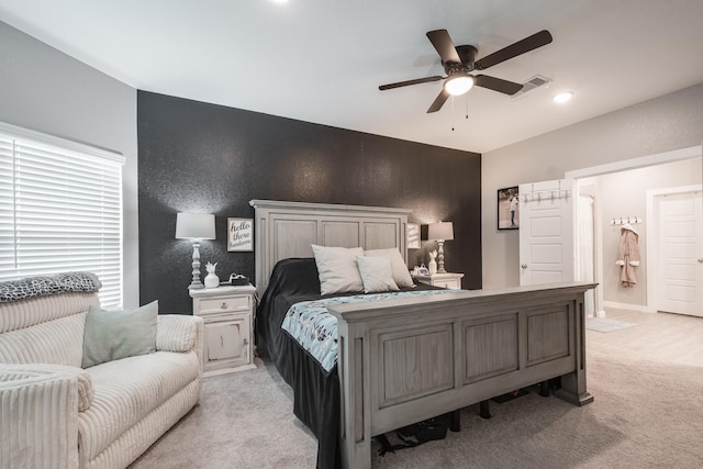 bedroom featuring a ceiling fan, visible vents, light carpet, and ensuite bathroom