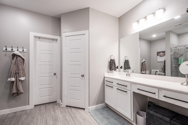 full bath featuring visible vents, a stall shower, wood finished floors, vanity, and baseboards