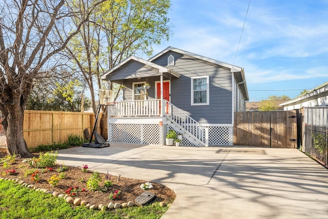 bungalow with a gate, fence, covered porch, and concrete driveway