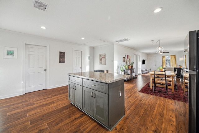 kitchen featuring gray cabinetry, freestanding refrigerator, dark wood-type flooring, and visible vents