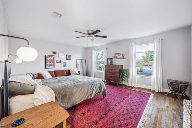 bedroom featuring baseboards, ceiling fan, wood finished floors, and visible vents