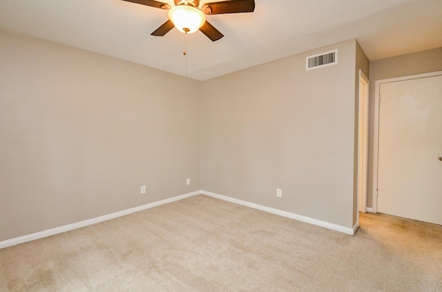 spare room with light colored carpet, a ceiling fan, visible vents, and baseboards