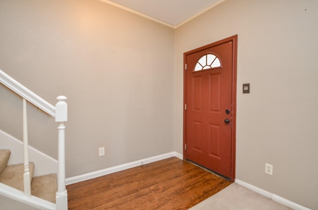 foyer with crown molding, baseboards, and stairway