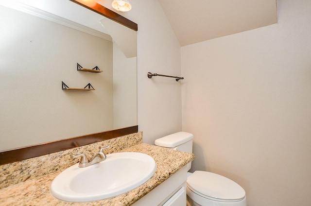 half bathroom with vanity, vaulted ceiling, and toilet