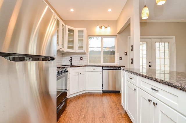 kitchen featuring decorative backsplash, glass insert cabinets, light wood-style floors, a sink, and stainless steel appliances