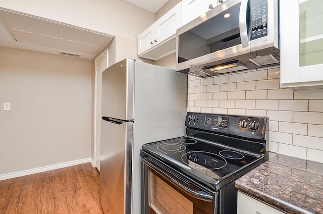 kitchen with visible vents, black range with electric stovetop, wood finished floors, stainless steel microwave, and white cabinetry