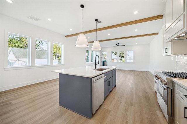 kitchen with light countertops, appliances with stainless steel finishes, a sink, and light wood-type flooring