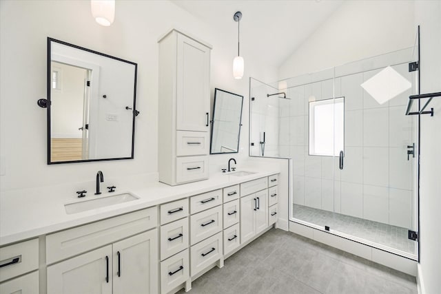 full bathroom with double vanity, a sink, lofted ceiling, and a stall shower