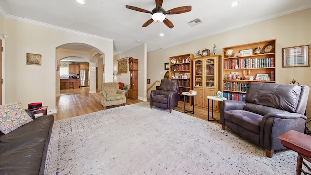 living room with arched walkways, ceiling fan, wood finished floors, and visible vents