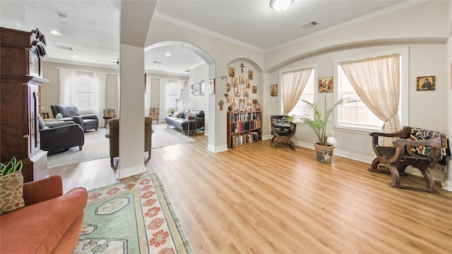foyer with visible vents, crown molding, arched walkways, baseboards, and light wood-style floors