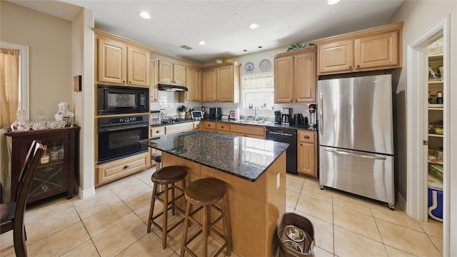kitchen featuring a kitchen breakfast bar, a center island, tasteful backsplash, a sink, and black appliances