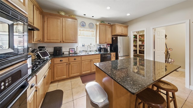 kitchen with a sink, a breakfast bar area, light tile patterned floors, tasteful backsplash, and black appliances