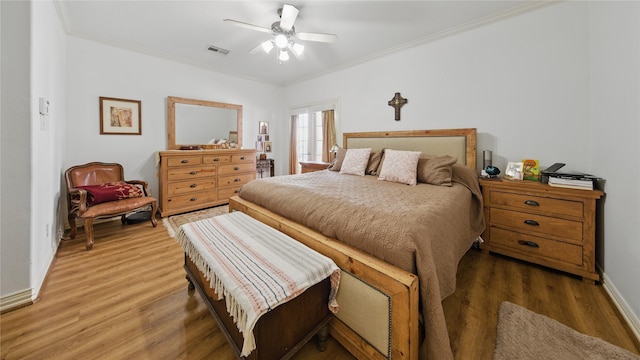 bedroom with visible vents, light wood-style floors, crown molding, and baseboards