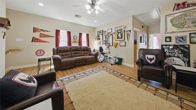 living room featuring ceiling fan, visible vents, wood finished floors, and attic access