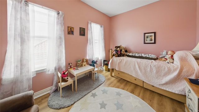 bedroom with baseboards, wood finished floors, and multiple windows
