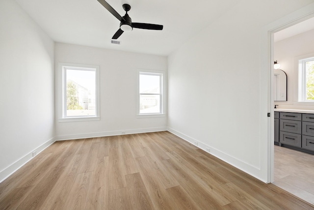 interior space featuring visible vents, baseboards, ceiling fan, light wood-type flooring, and connected bathroom