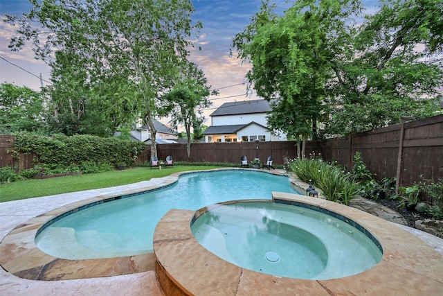 5217 Beech St, Bellaire, TX 77401 - pool at dusk featuring a lawn, a pool with connected hot tub, and a fenced backyard