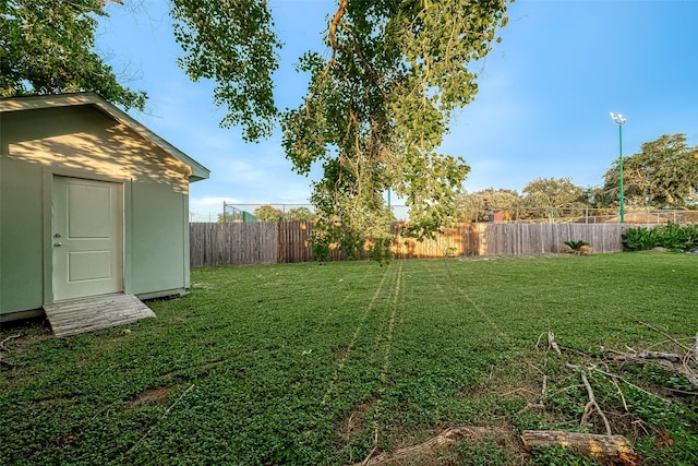 view of yard featuring an outdoor structure, a fenced backyard, and a shed