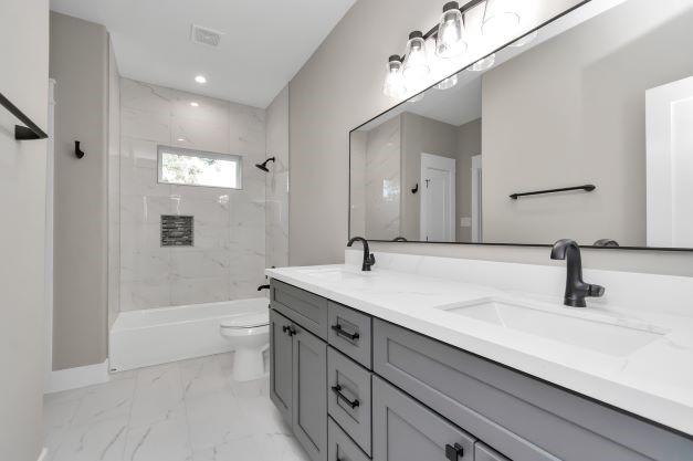 bathroom featuring double vanity, a sink, marble finish floor, and toilet
