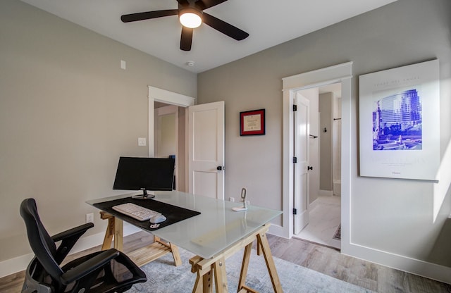 office space featuring ceiling fan, baseboards, and light wood finished floors