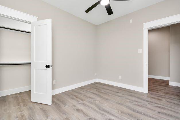 unfurnished bedroom featuring baseboards, vaulted ceiling, wood finished floors, and a closet