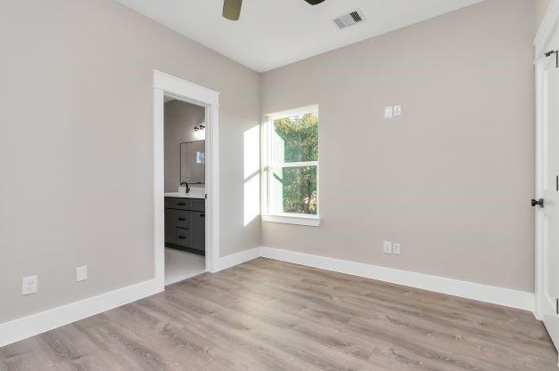 interior space with ceiling fan, visible vents, a sink, baseboards, and light wood-style flooring