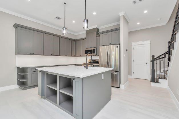 kitchen featuring crown molding, open shelves, gray cabinetry, and stainless steel appliances
