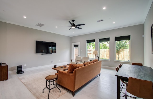 living room featuring crown molding, baseboards, a ceiling fan, and visible vents