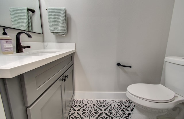 bathroom with baseboards, tile patterned floors, toilet, and vanity