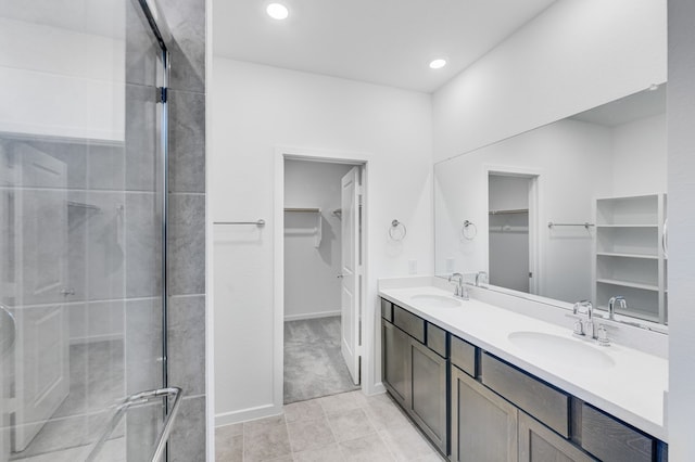 full bath featuring double vanity, a walk in closet, a sink, and a stall shower