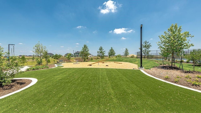 view of community featuring a lawn and fence