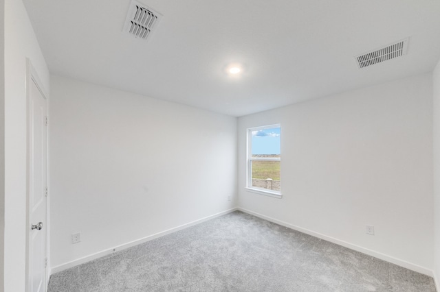 carpeted spare room featuring baseboards and visible vents