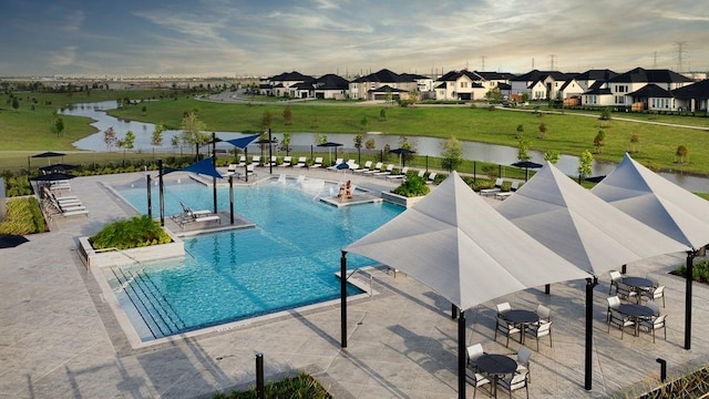 community pool featuring a water view, a patio area, fence, and a residential view