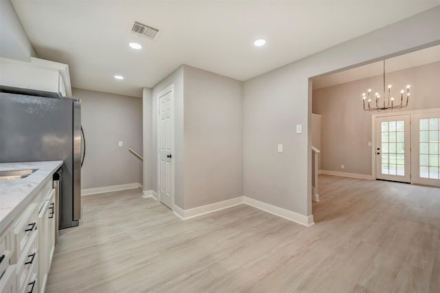 kitchen featuring white cabinets, a chandelier, baseboards, light wood-type flooring, and visible vents
