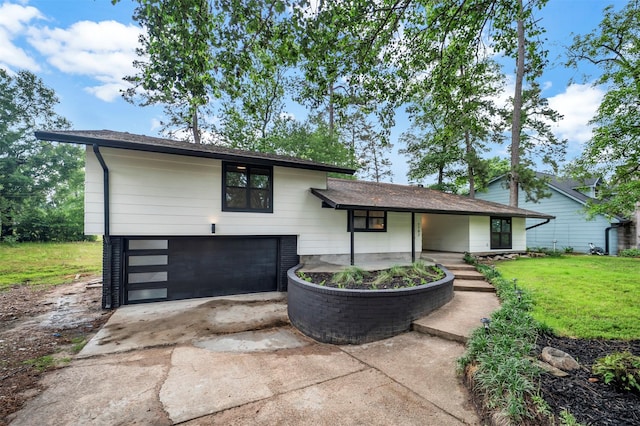 split level home featuring concrete driveway, an attached garage, and a front lawn
