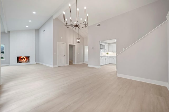 unfurnished living room featuring an inviting chandelier, visible vents, light wood-style floors, baseboards, and high vaulted ceiling