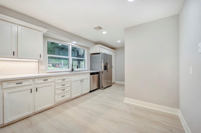 kitchen featuring a sink, appliances with stainless steel finishes, baseboards, and light wood-style flooring