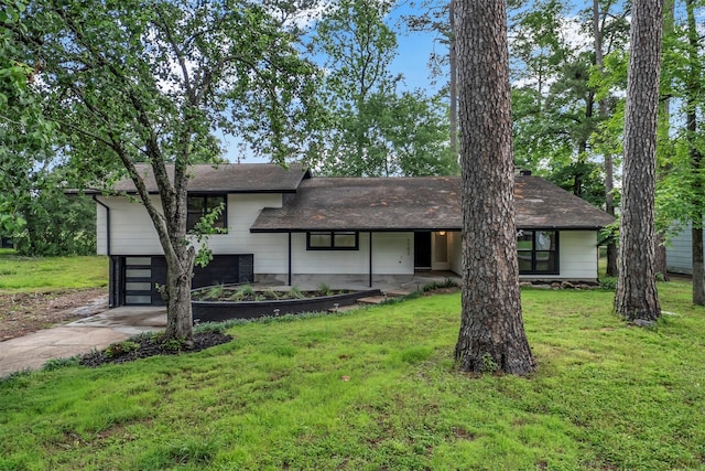 view of front of house featuring a garage, a front lawn, roof with shingles, and driveway