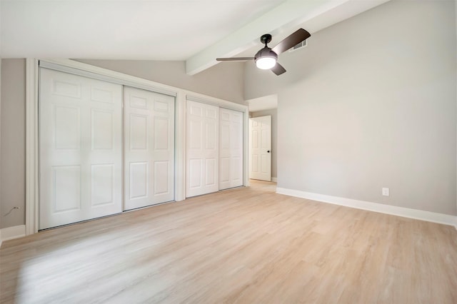 unfurnished bedroom featuring a ceiling fan, baseboards, two closets, vaulted ceiling with beams, and light wood-style flooring