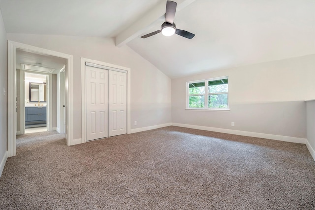 unfurnished bedroom with baseboards, lofted ceiling with beams, carpet, and a closet