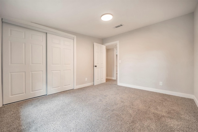 unfurnished bedroom with baseboards, visible vents, carpet, and a closet