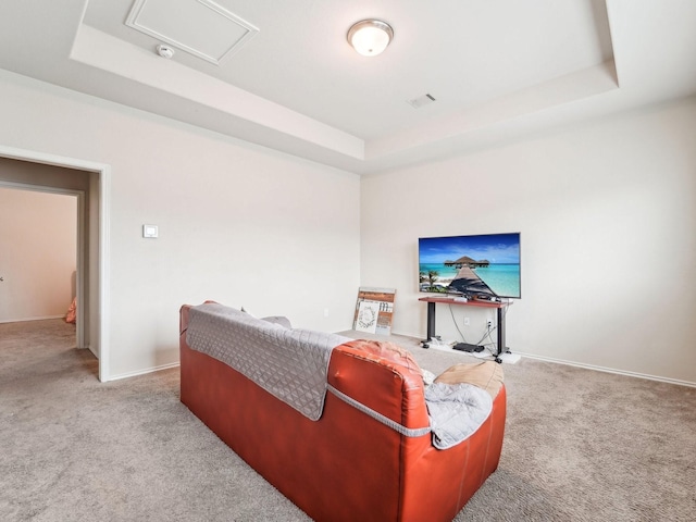 living room featuring carpet floors, attic access, a raised ceiling, and baseboards