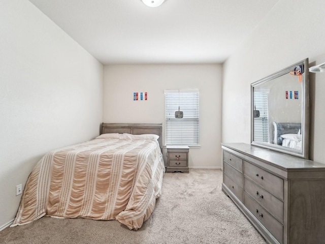 bedroom with light colored carpet and baseboards