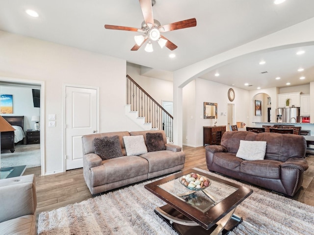 living area featuring light wood-type flooring, arched walkways, and recessed lighting