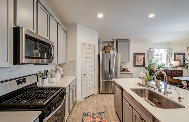 14543 Rain Tree Dr, Baytown, TX 77523 - kitchen with appliances with stainless steel finishes, a sink, light countertops, gray cabinets, and light wood-style flooring