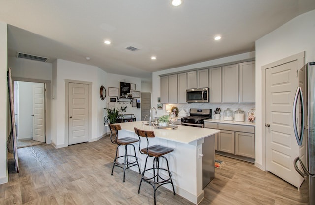 14543 Rain Tree Dr, Baytown, TX 77523 - kitchen with visible vents, a breakfast bar area, a sink, gray cabinetry, and stainless steel appliances