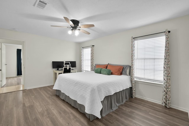 bedroom with visible vents, a ceiling fan, baseboards, and wood finished floors