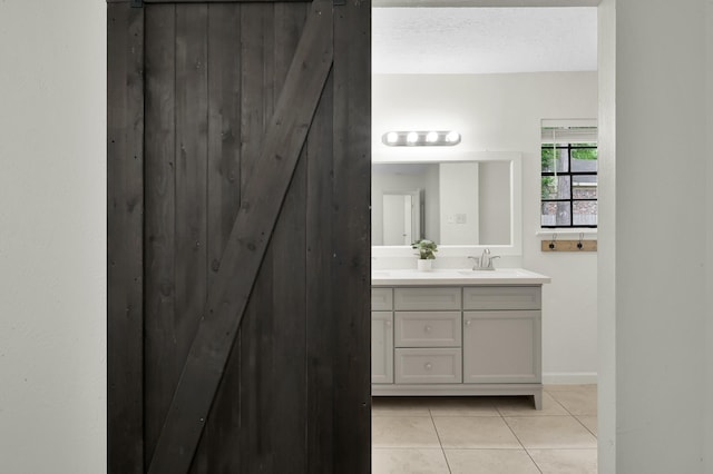 bathroom with double vanity, tile patterned floors, baseboards, and a sink