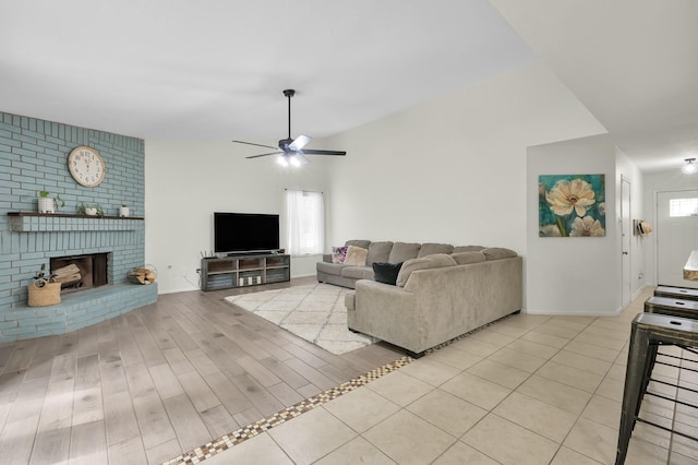 living room featuring baseboards, ceiling fan, a brick fireplace, and light wood finished floors