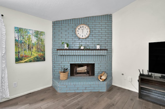 living area featuring a brick fireplace, baseboards, and wood finished floors